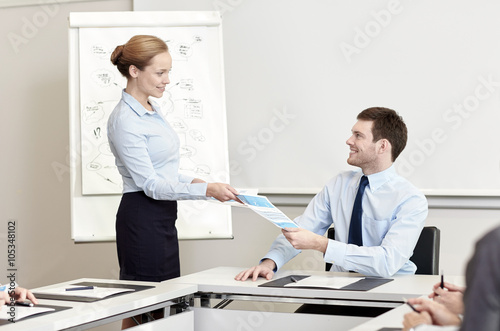 smiling woman giving papers to man in office