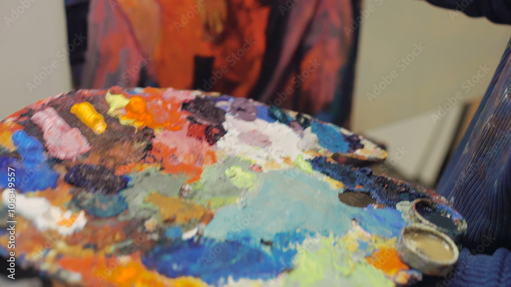 artist brush mix color oil painting on palette is holding in his hand closeup artist brush mix color oil painting on palette is holding in his hand closeup