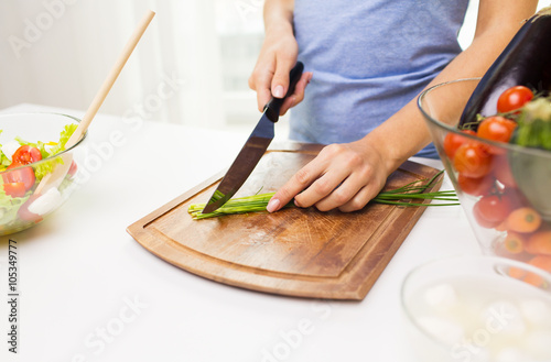 close up of woman chopping green onion with knife