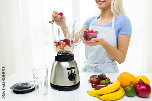 close up of woman with blender making fruit shake