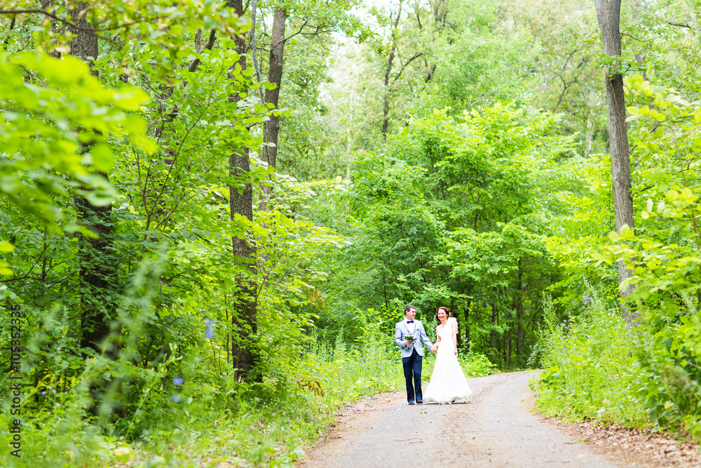 Bride and groom at wedding Day walking Outdoors on spring nature. Happy Newlywed  embracing in green park. 