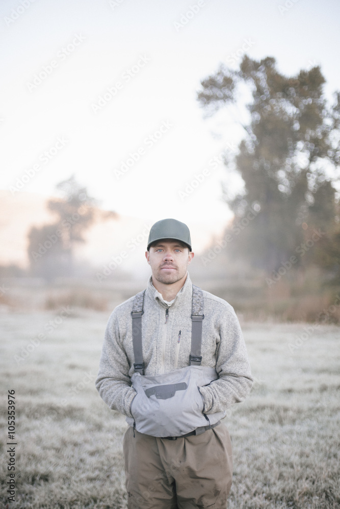 A fisherman standing with hands in his pockets in the dawn light, A fisherman standing with hands in his pockets in the dawn light,