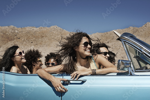 Friends in blue convertible on mountain road photo