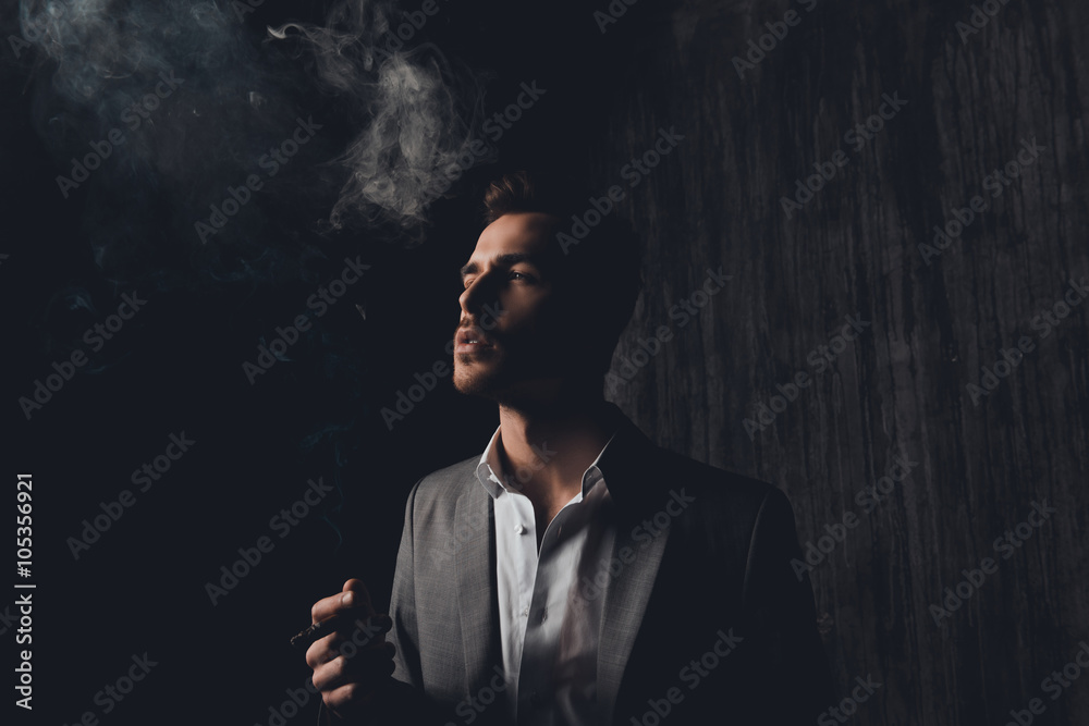 Successful businessman with cigar and smoke on black background