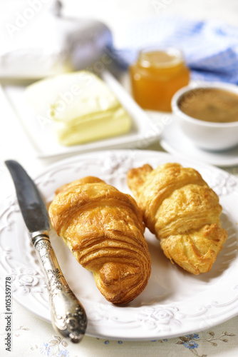 Croissant with butter,honey and cup of coffee.