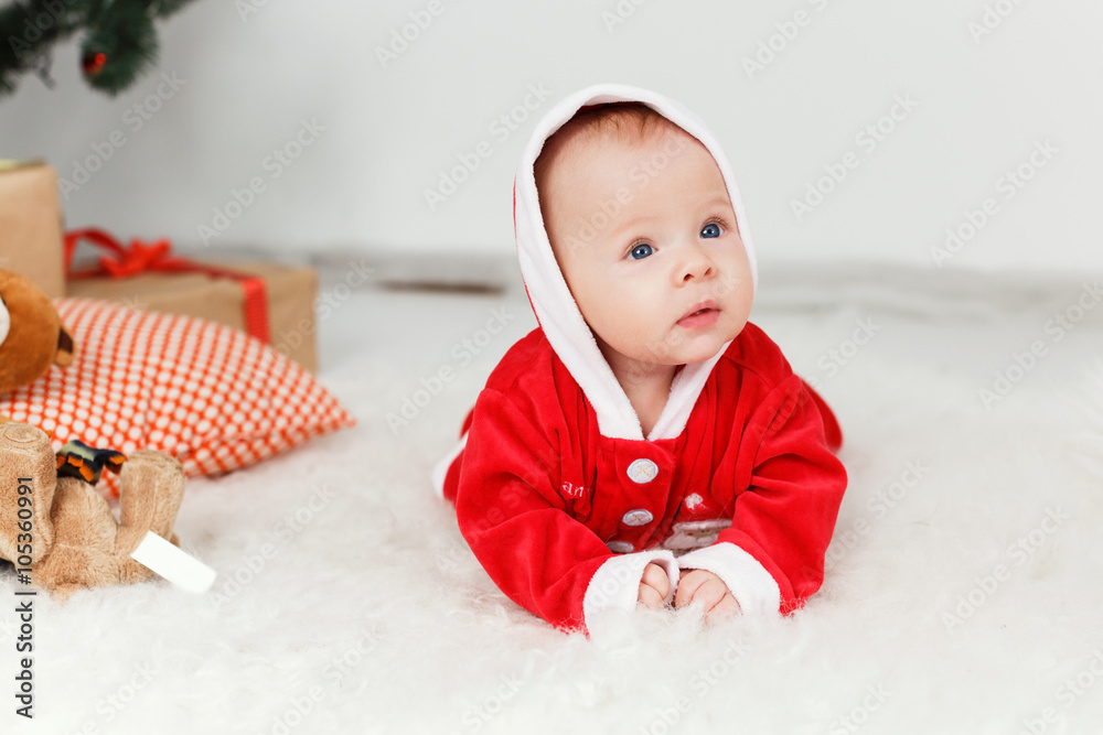 Pretty little baby in red costume lying on the floor Pretty little baby in red costume lying on the floor