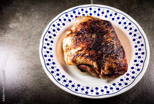 Obraz na plátně roasted pork ham in a dish on dark flat stone ambient