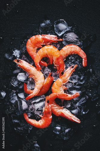 Food background, frozen cooked shrimp with ice, black background photo