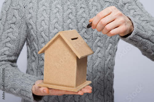 Man in gray sweater holding little wooden house