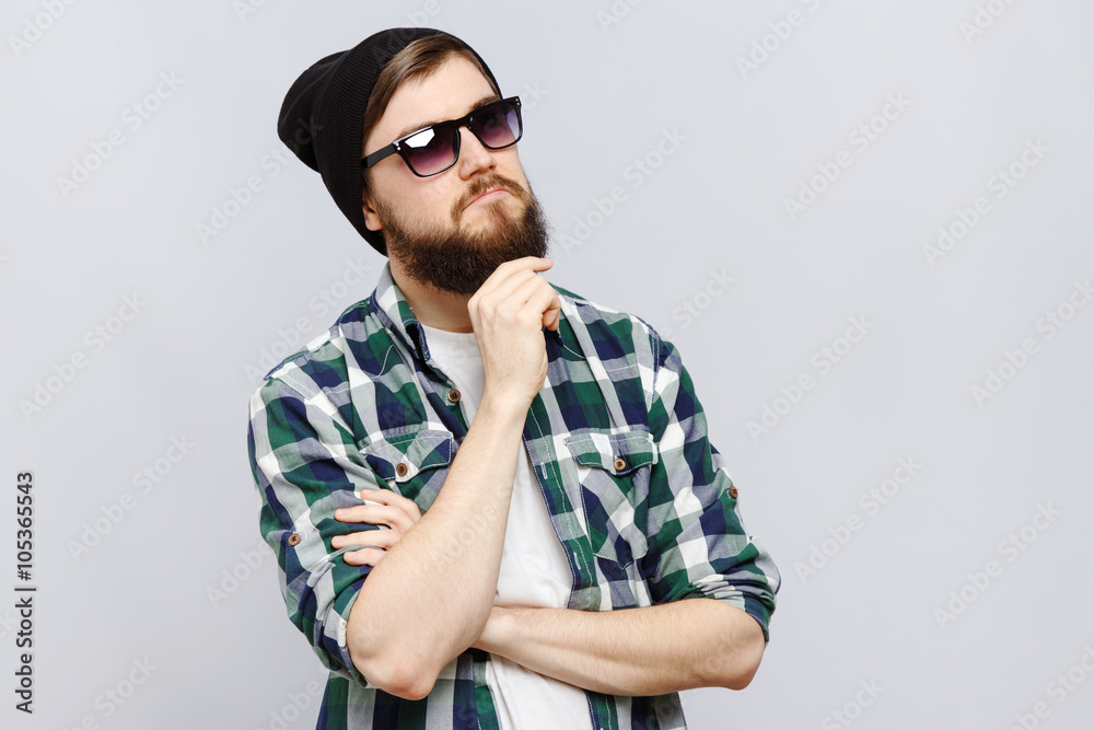 Serious young man posing with hand touching his beard Serious young man posing with hand touching his beard