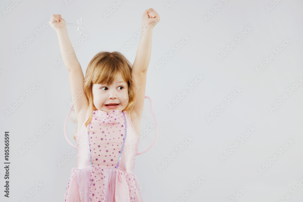 Cheerful little girl puts her hands up with magic stick Cheerful little girl puts her hands up with magic stick