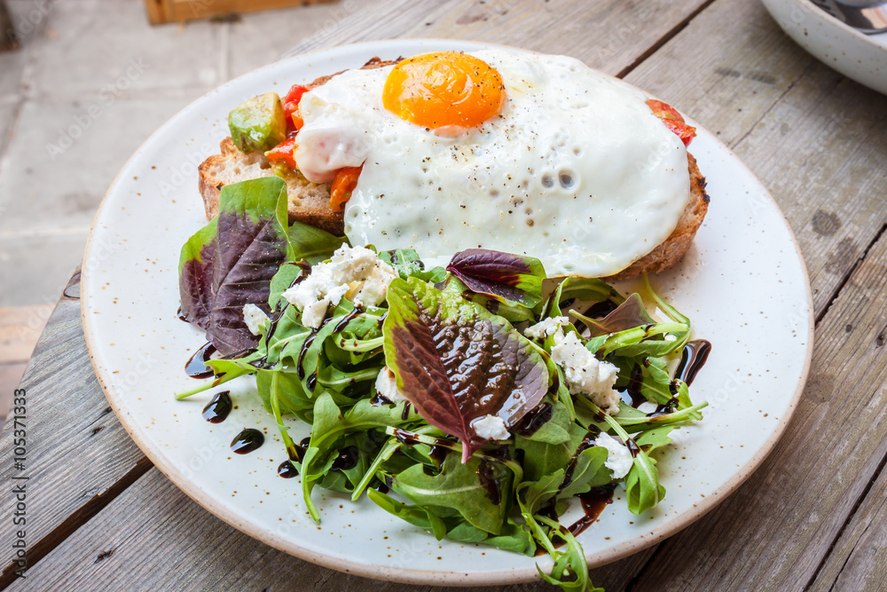 Salad with fried egg on a wood table Salad with fried egg on a wood table