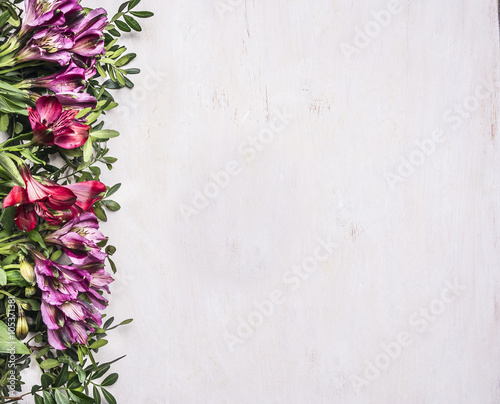 beautiful freesya multicolored flowers with green leaves border ,place for text  on wooden rustic background top view photo