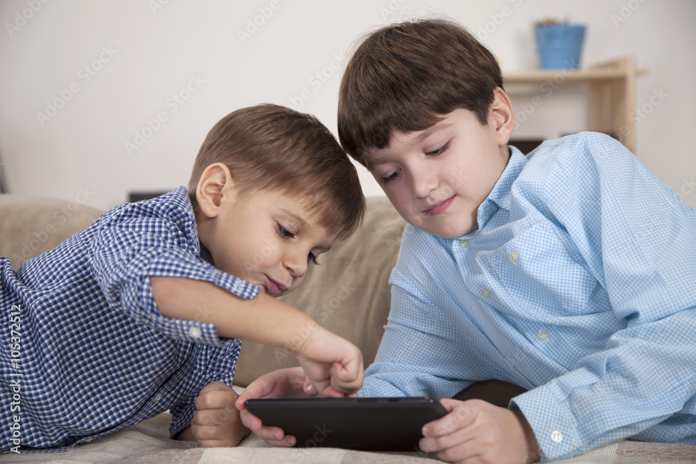 Boys playing on tablet computer in the living room Boys playing on tablet computer in the living room