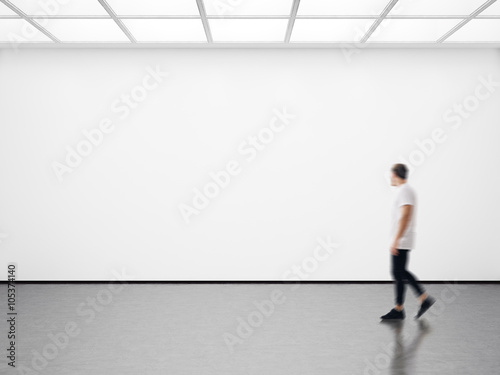 Photo of hipster in modern gallery looking at the empty canvas. Blank mockup, motion blur 