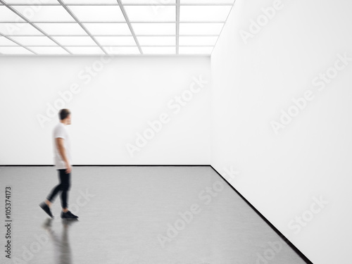Photo of young man in modern gallery looking at the empty canvas. Blank mockup, motion blur 