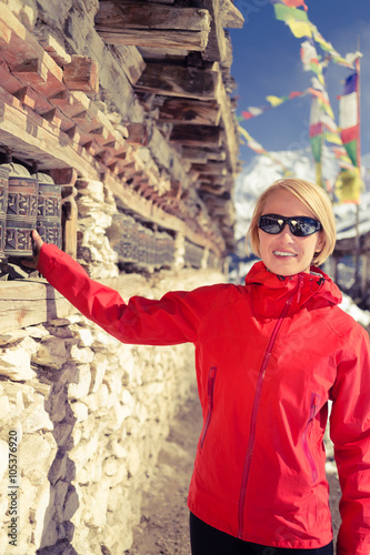 Happy woman hiker and prayer wheel in Nepal