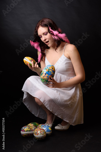 Ung tjej med påskägg och påskfjädrar i håret photo