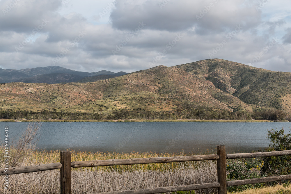 Clouds covering a mountain range with a lake and fence in the foreground at Otay Lakes County Park in Chula Vista, California Clouds covering a mountain range with a lake and fence in the foreground at Otay Lakes County Park in Chula Vista, California