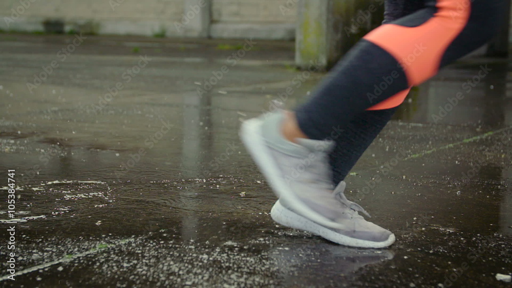 Female athletes running shoes close up on wet urban asphalt. Outdoor city workout under the rain.