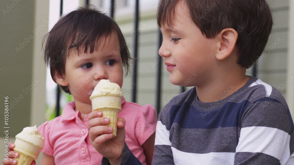 Brother and sister eating ice cream cones together