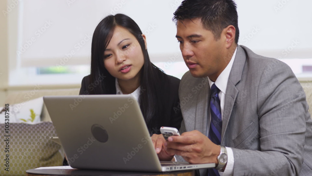 Business man and woman using laptop in office lobby Business man and woman using laptop in office lobby