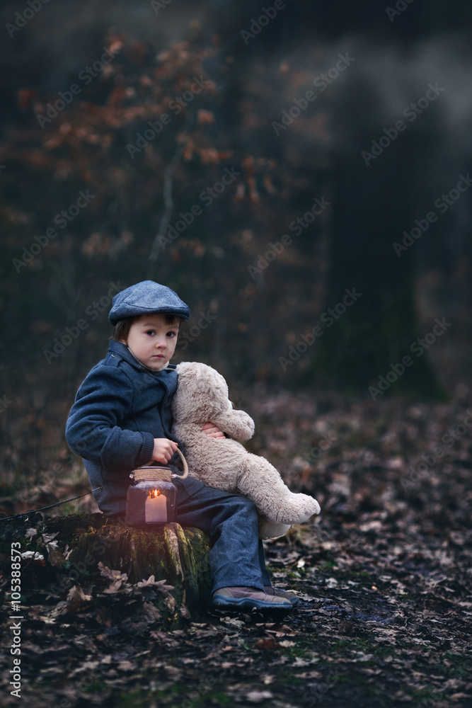 Cute little child, holding lantern and teddy bear in forest Cute little child, holding lantern and teddy bear in forest