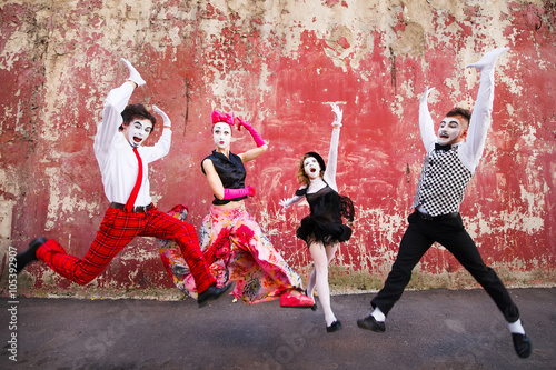 Four mimes jumping on a background of a red wall. photo