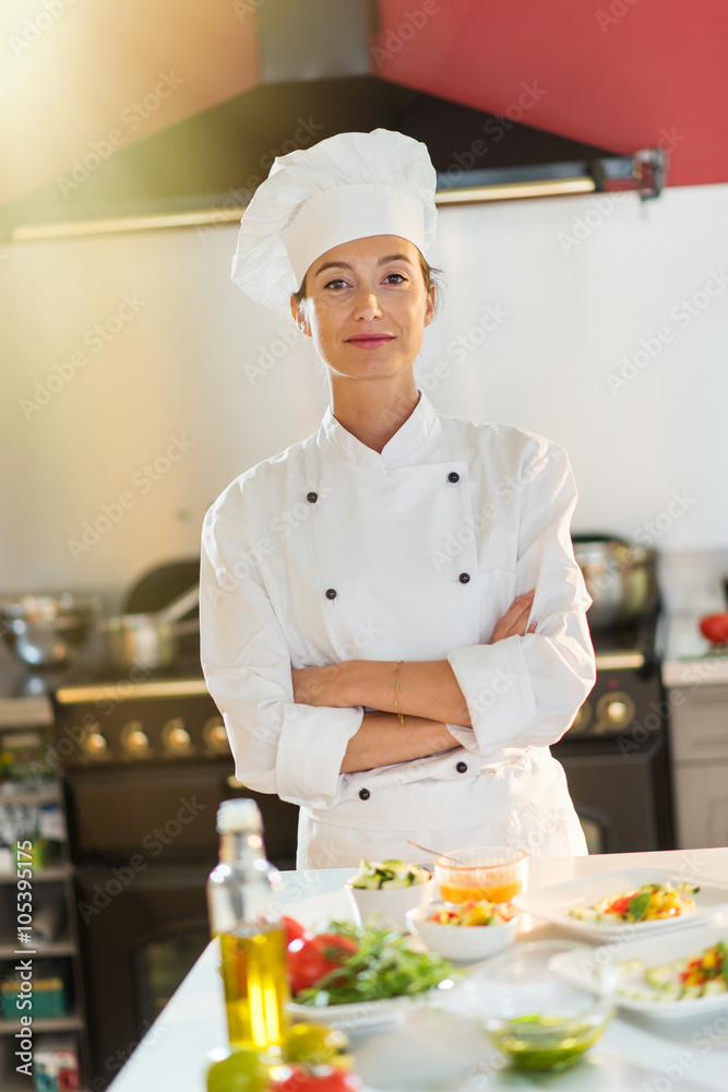 Portrait of a woman chef standing in the kitchen arms crossed. Portrait of a woman chef standing in the kitchen arms crossed.