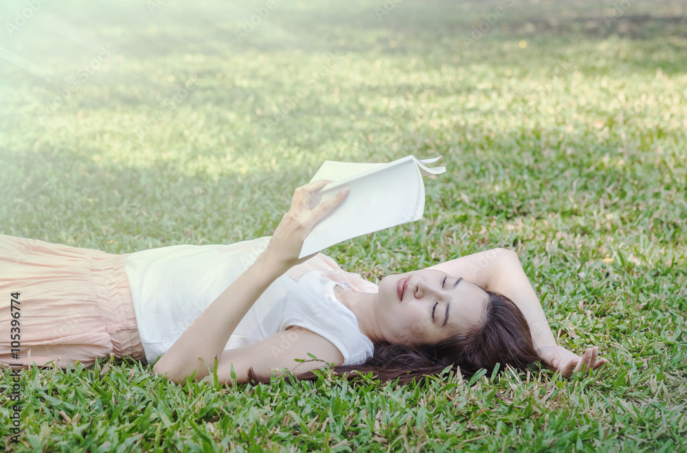 Woman lying on grass field for reading in the park Woman lying on grass field for reading in the park