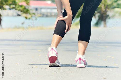 Woman runner leg and muscle pain during running outdoors in summ