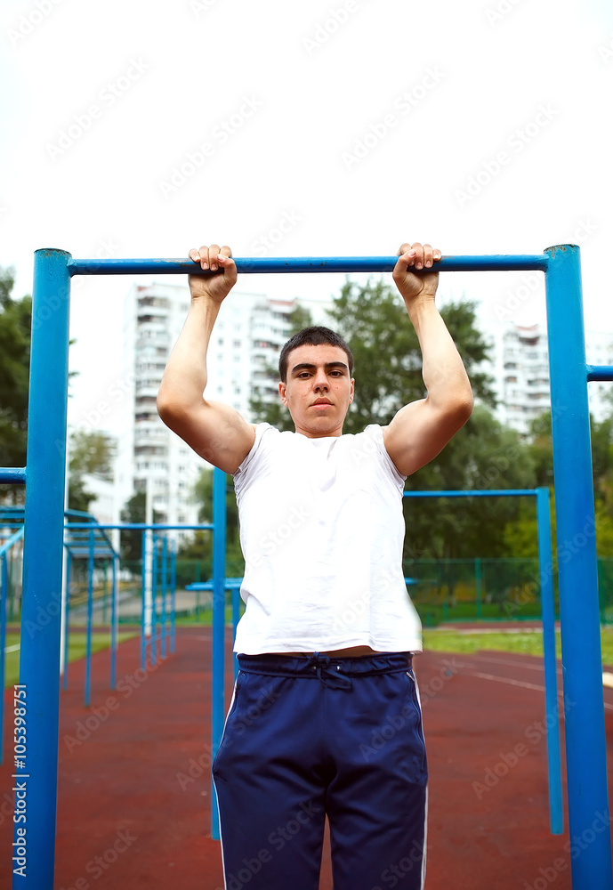 Obraz premium Muscular man doing pull-ups on horizontal bar