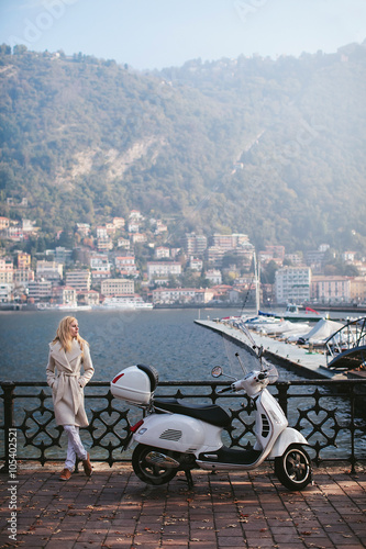 girl standing next to a moped on the waterfront of Lake Como