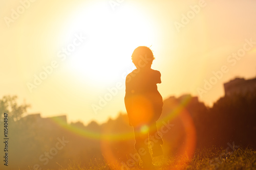 silhouette of little boy running at sunset