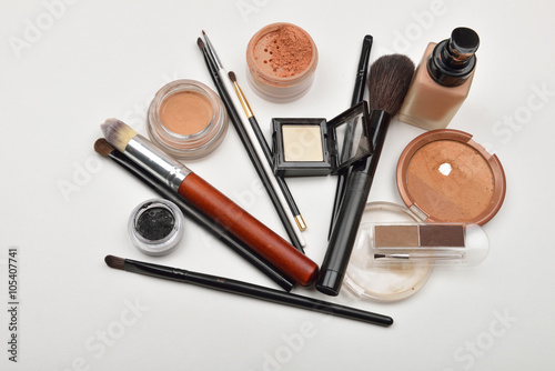 Close-up of open liquid foundation bottle, jar of loose powder,