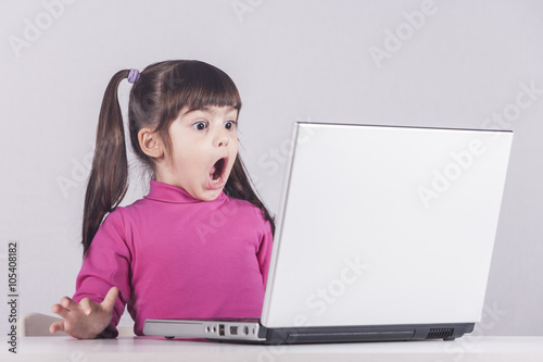 Little girl reacts while using a laptop. Internet safety concept