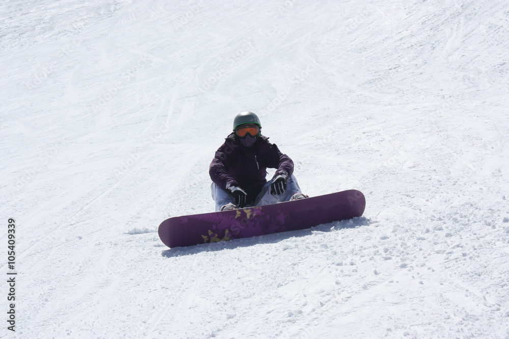Young snowboarder woman sitting on the ski slope.