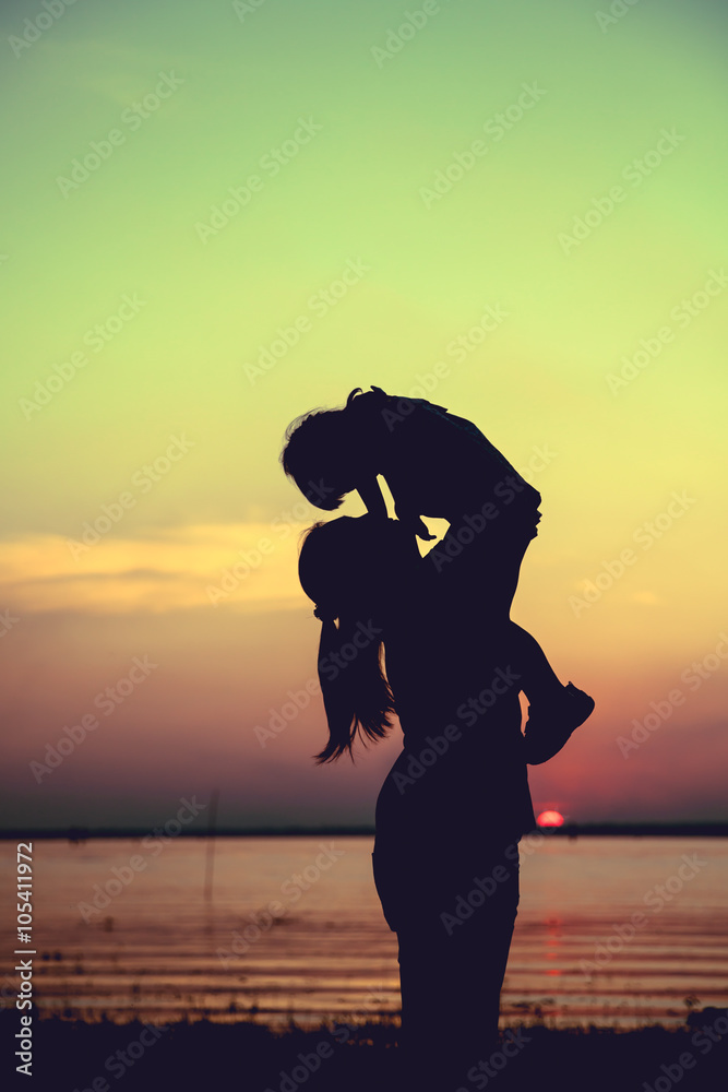 Fototapeta premium Silhouette of mother and child enjoying the view at riverside. 