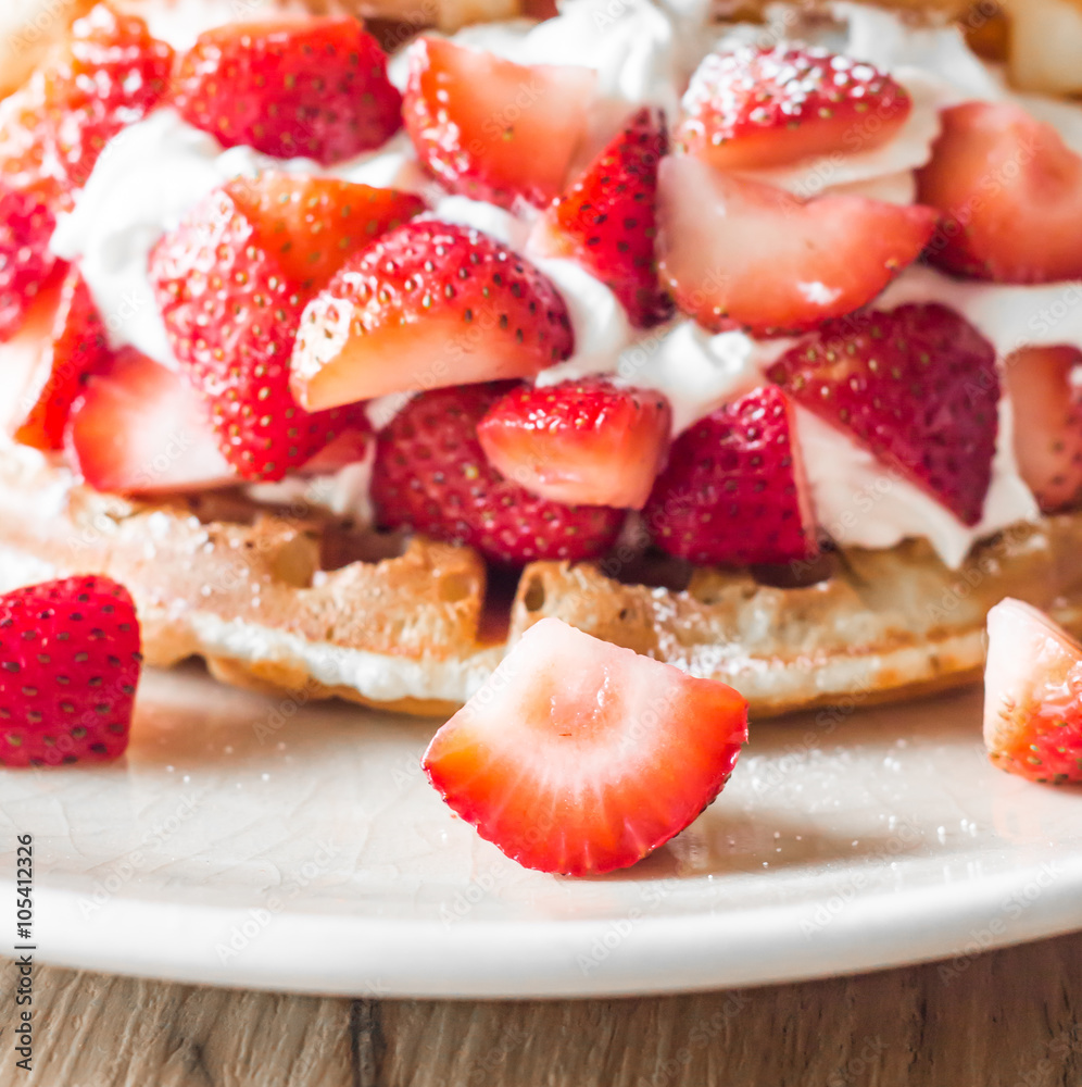 Strawberries waffles with vanilla ice cream on white plate.