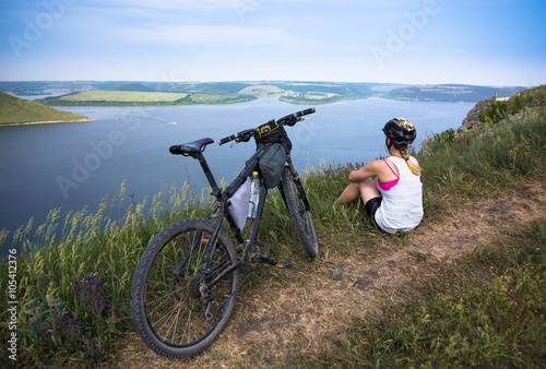 Young bicyclist relax in beautiful nature near river. Hot sunny summer day
