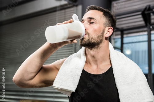 Muscular man drinking protein shake photo