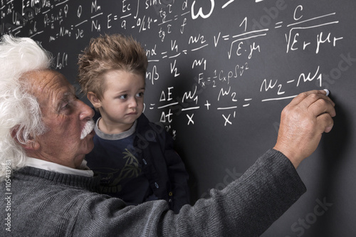 Nonno scienziato che scrive alla lavagna con nipotino in braccio photo