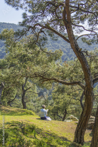 background landscape view of a woman painting, sitting in the woods on a hillside on Yorgey Biyukada Island in Istanbul, Turkey
