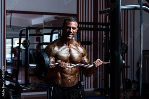 Bodybuilder Exercising Biceps With Barbell In Gym © Jale Ibrak