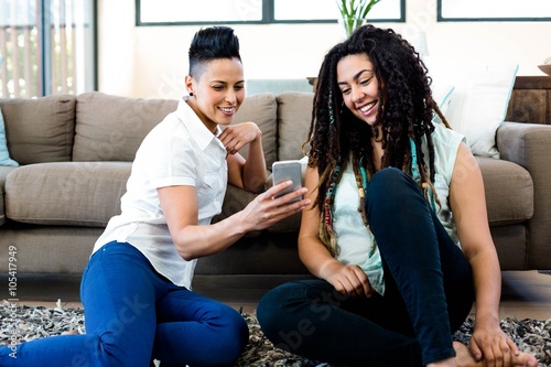 Smiling lesbian couple sitting and looking at their phone