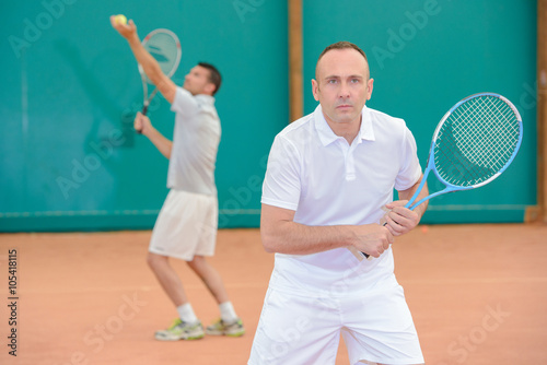 Two men playing doubles tennis © auremar