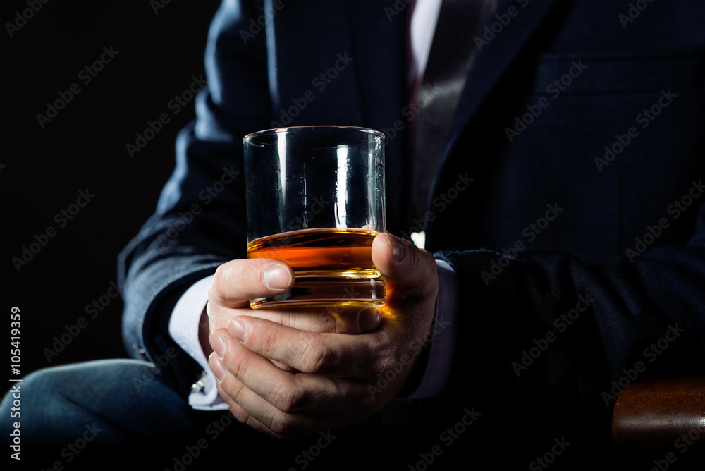 Closeup of serious businessman holding  glass of whiskey illustrate executive privilege concept. 