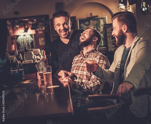 Photography Cheerful old friends having fun and drinking draft beer at bar counter in pub