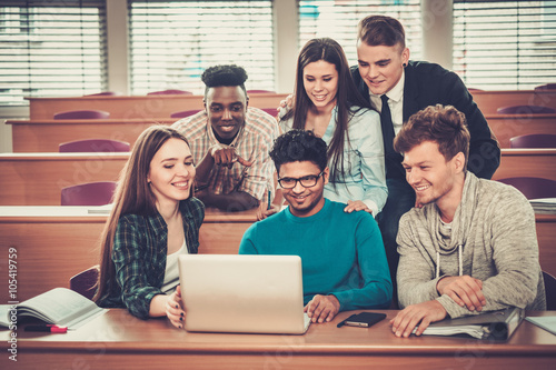 Multinational group of cheerful students taking an active part in a lesson while sitting in a lecture hall. photo