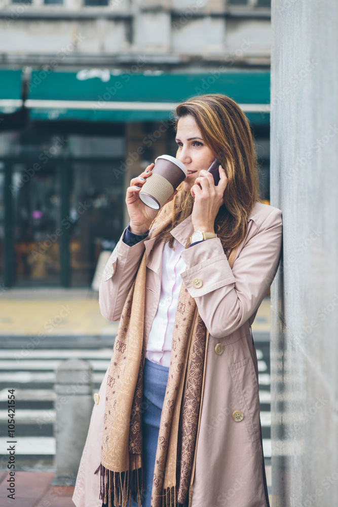 Fototapeta premium Young woman at the street drinking coffee and talking on the phone 